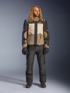 Casaco Alpinestars Andes V4 Drystar®, Walnut Mastic Black, usado com calças e luvas de motociclismo pretas, com um design de aventura multi-painel com detalhes laranja e logótipos Alpinestars, equipamento têxtil técnico para condução em todas as condições climatéricas