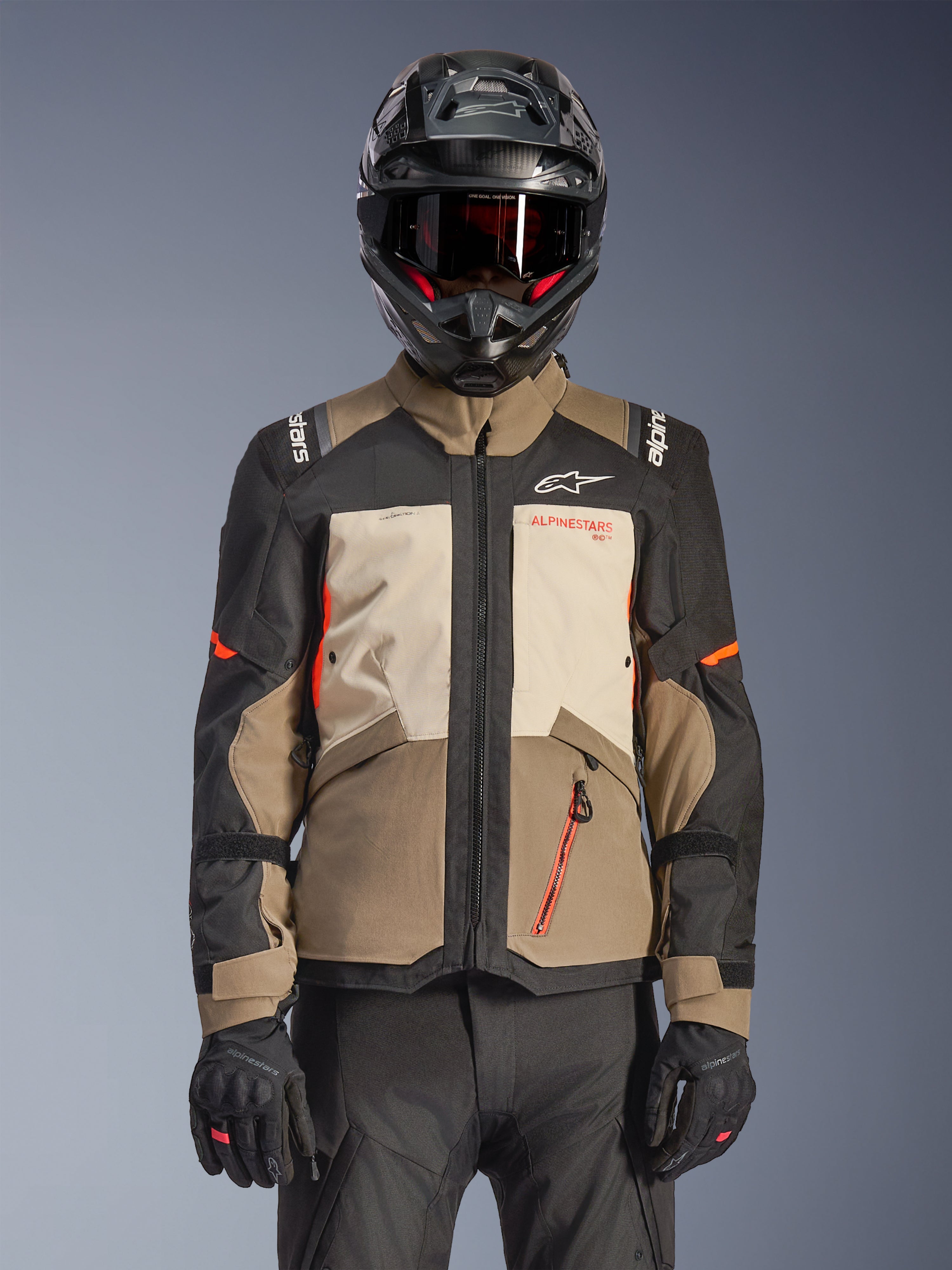 Alpinestars Andes V4 Drystar® Jacket, Walnut Mastic Black, casaco adventure touring com painéis castanho nogueira e creme mastic, mangas pretas e detalhes em laranja vibrante, usado com capacete de motociclismo preto, óculos escuros e luvas pretas