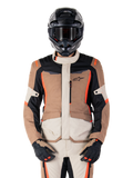 Alpinestars ST-1 Waterproof Jacket, casaco impermeável, Dark Khaki Sand Black Red Fluo, usado por um motociclista com capacete e luvas pretas, equipamento de aventura touring com painéis beges e castanhos e detalhes em vermelho fluorescente vibrante, vista frontal sobre fundo branco