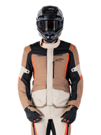 Alpinestars ST-1 Waterproof Jacket, casaco impermeável, Dark Khaki Sand Black Red Fluo, usado por um motociclista com capacete e luvas pretas, equipamento de aventura touring com painéis beges e castanhos e detalhes em vermelho fluorescente vibrante, vista frontal sobre fundo branco