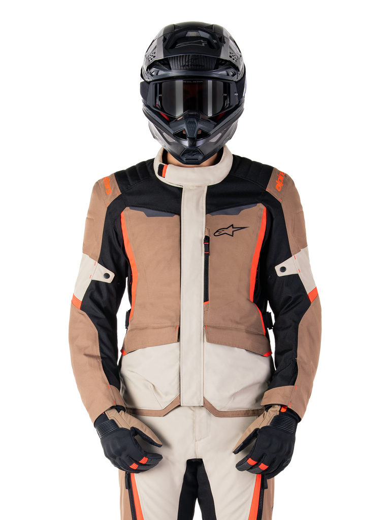 Alpinestars ST-1 Waterproof Jacket, casaco impermeável, Dark Khaki Sand Black Red Fluo, usado por um motociclista com capacete e luvas pretas, equipamento de aventura touring com painéis beges e castanhos e detalhes em vermelho fluorescente vibrante, vista frontal sobre fundo branco