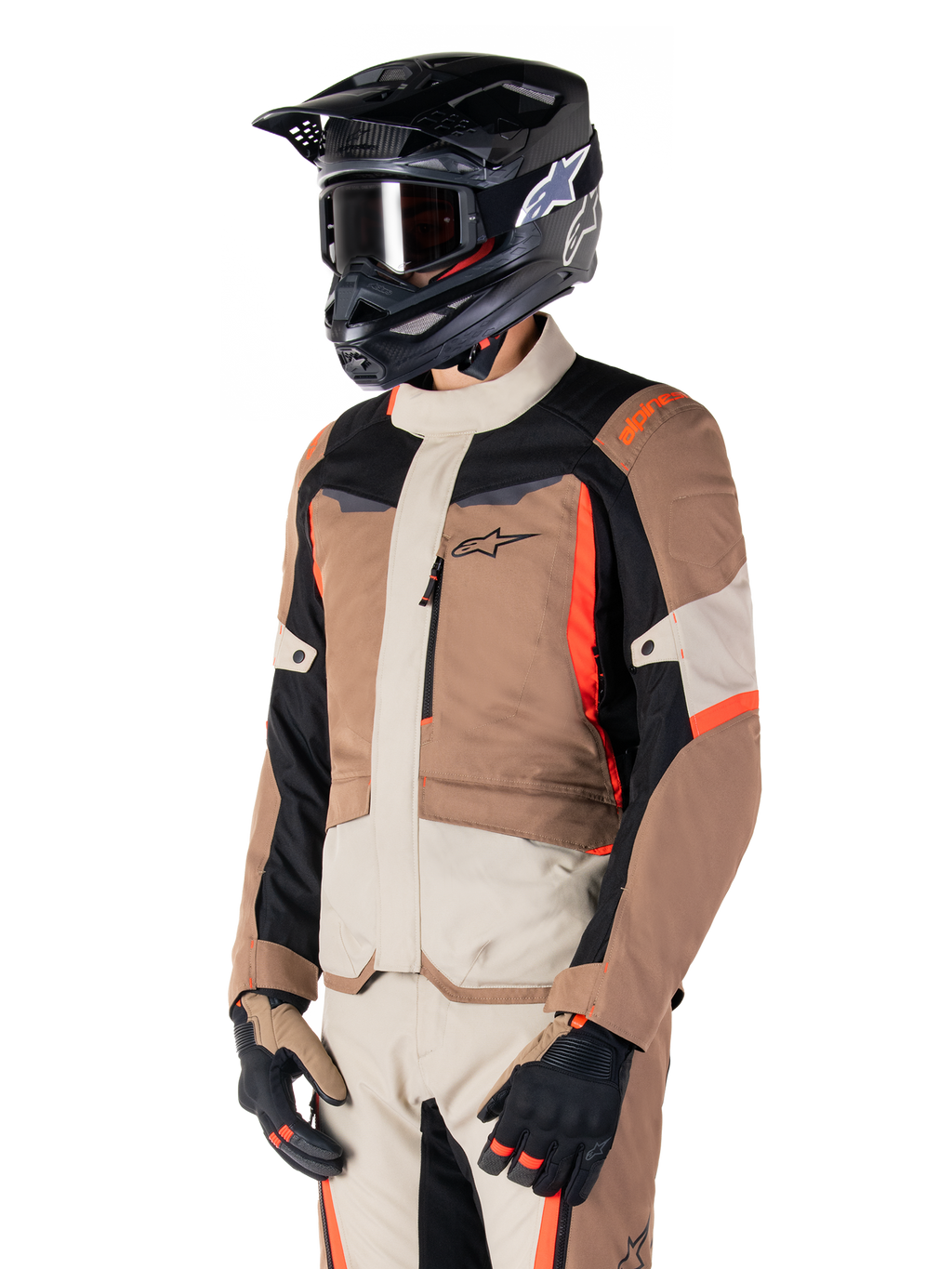 Casaco Alpinestars ST-1 Waterproof, casaco de touring de aventura, Dark Khaki Sand Black e Red Fluo, usado por um piloto com capacete de motocross preto e óculos de proteção, com design de vários painéis, bolsos cargo e logótipo Alpinestars no peito
