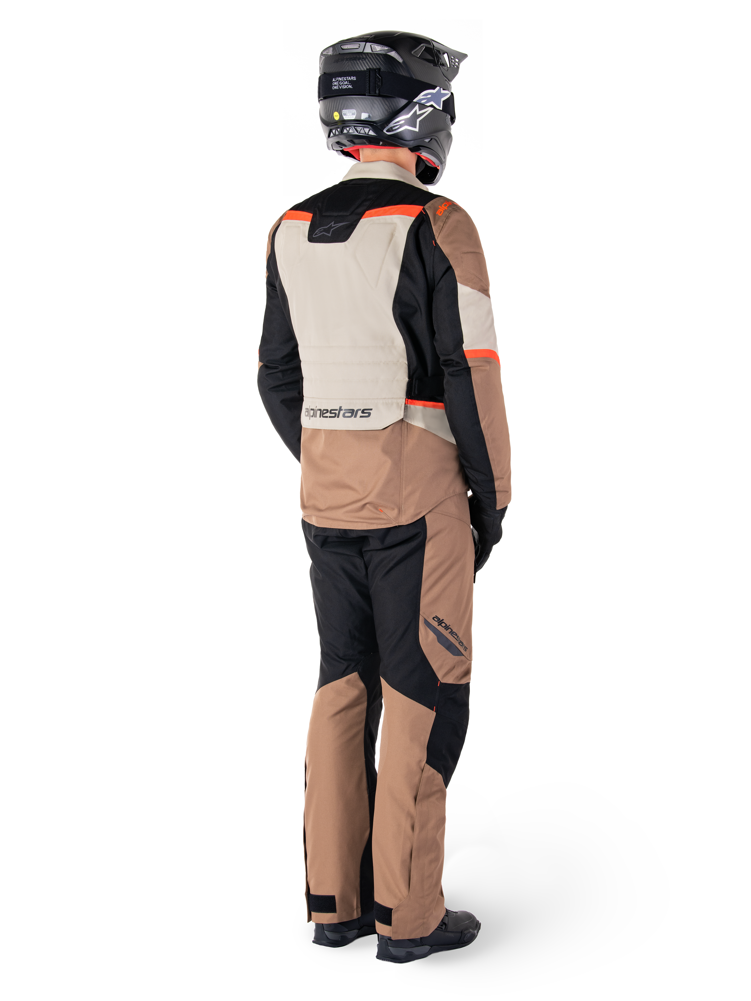 Casaco Impermeável Alpinestars ST-1, casaco de turismo de aventura, Dark Khaki Sand Black Red Fluo, vista traseira, usado com calças a condizer e capacete preto, com painéis em blocos de cores e detalhes em vermelho fluorescente.