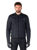 Casaco Alpinestars Clayton WR, casaco de motociclismo preto, vestido por modelo, com detalhes acolchoados nos ombros e grafismos técnicos, fecho de correr Vislon central, bolsos verticais com fecho de correr, pequeno logótipo branco no peito, equipamento de condução urbana para uso em estrada