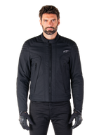 Casaco Alpinestars Clayton WR, casaco de motociclismo preto, vestido por modelo, com detalhes acolchoados nos ombros e grafismos técnicos, fecho de correr Vislon central, bolsos verticais com fecho de correr, pequeno logótipo branco no peito, equipamento de condução urbana para uso em estrada