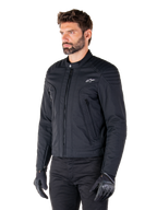 Casaco Alpinestars Clayton WR, preto, casaco de motociclista urbano em tecido com detalhes acolchoados nos ombros e antebraços, design de corte slim, acabamento fosco, usado por um motociclista com luvas pretas