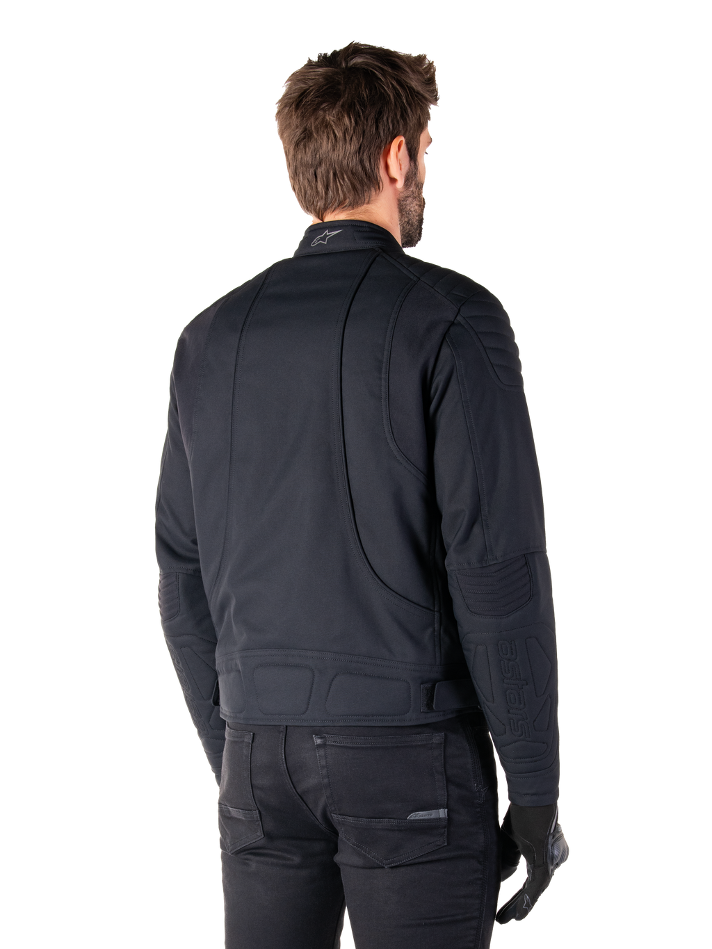 Casaco Alpinestars Clayton WR em preto, vista traseira de três quartos num modelo masculino, casaco de motociclista urbano com acolchoado nos ombros e cotovelos, linhas de costura técnicas e logótipo refletor na gola, combinado com calças e luvas pretas