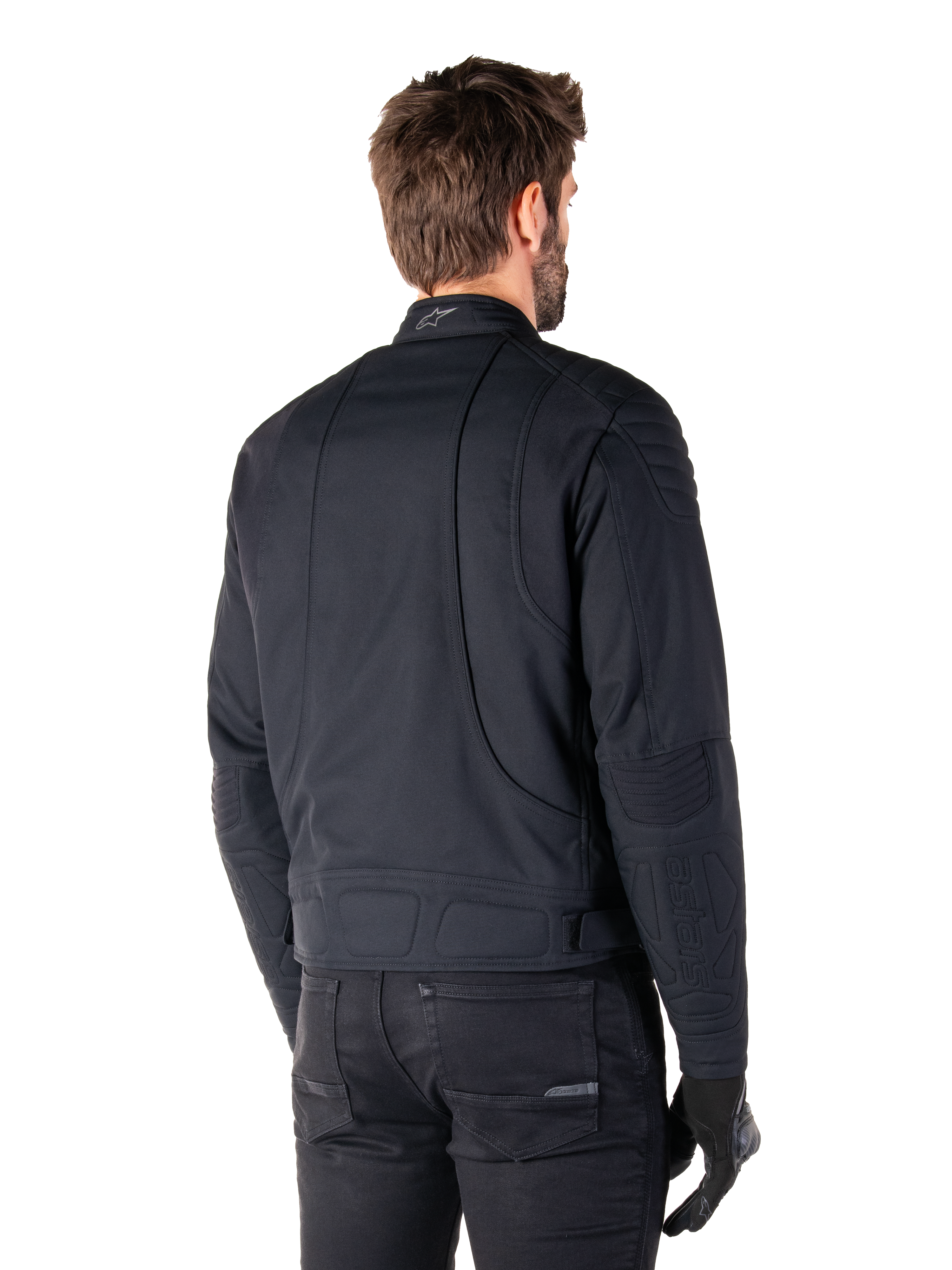 Casaco Alpinestars Clayton WR em preto, vista traseira de três quartos num modelo masculino, casaco de motociclista urbano com acolchoado nos ombros e cotovelos, linhas de costura técnicas e logótipo refletor na gola, combinado com calças e luvas pretas