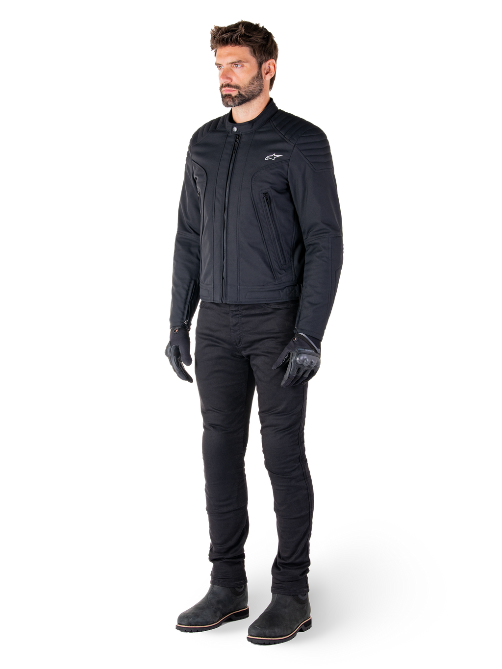 Motociclista a usar o Casaco Alpinestars Clayton WR, casaco de motociclista urbano preto, design de corte slim com pormenores acolchoados nos ombros e acabamento mate, combinado com calças técnicas de condução e luvas pretas.