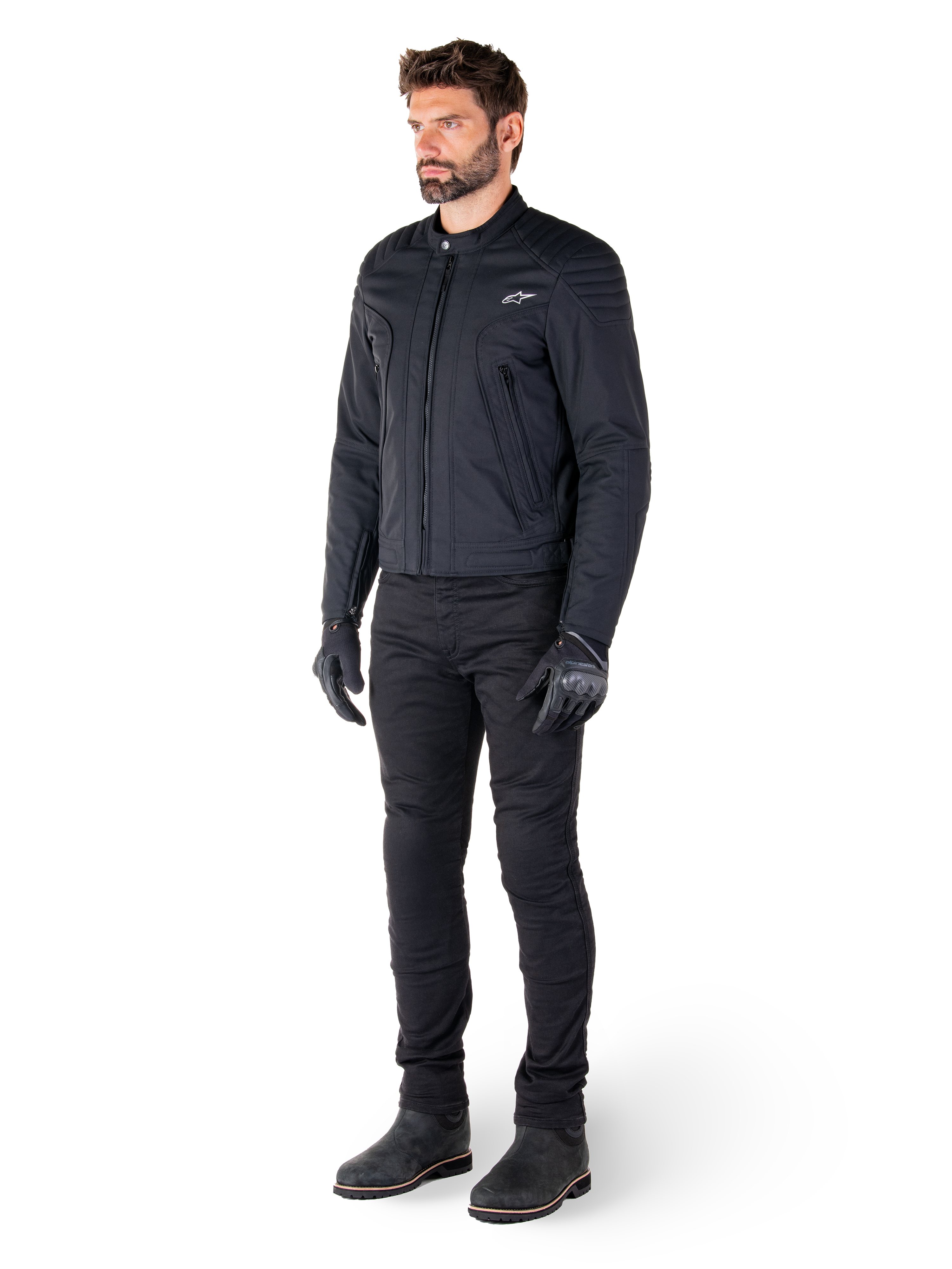Motociclista a usar o Casaco Alpinestars Clayton WR, casaco de motociclista urbano preto, design de corte slim com pormenores acolchoados nos ombros e acabamento mate, combinado com calças técnicas de condução e luvas pretas.