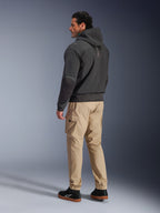 Casaco Alpinestars Moblast WP, hoodie técnico de motociclismo em preto, vista lateral e posterior, usado com calças cargo bege e sapatilhas pretas, apresentando um design com capuz, construção em têxtil técnico e uma estética urbana moderna.