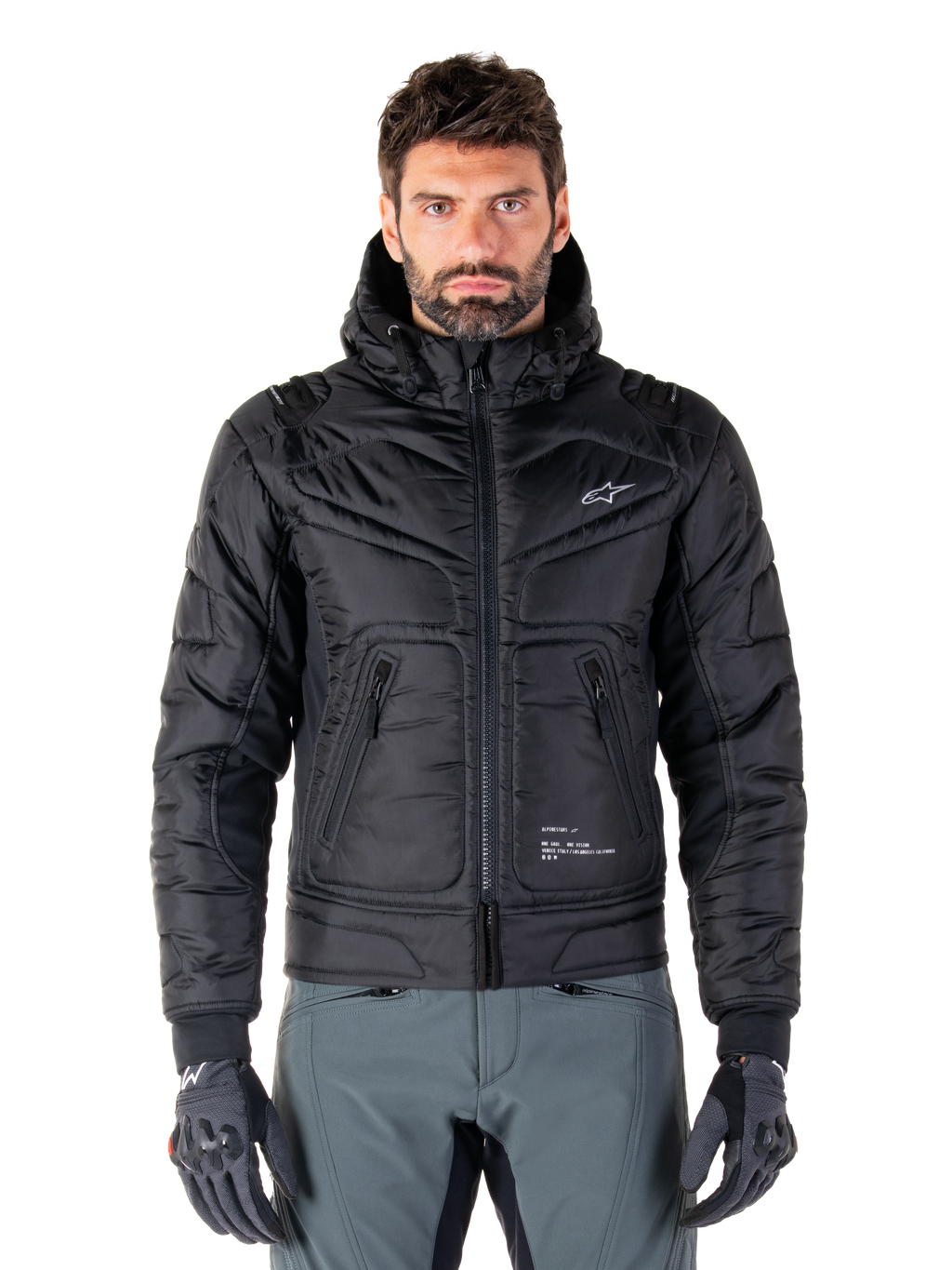 Alpinestars Mohobbs Waterproof Jacket, Black Padded Bomber Motorcycle Jacket, quilted poly fabric with front zipper and zippered pockets, small white logo on chest, worn by a model with grey pants and gloves, urban streetwear design for city riding.