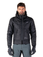 Alpinestars Mohobbs Waterproof Jacket, Black Padded Bomber Motorcycle Jacket, quilted poly fabric with front zipper and zippered pockets, small white logo on chest, worn by a model with grey pants and gloves, urban streetwear design for city riding.