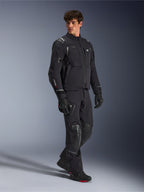 Casaco Alpinestars Andes Pro Drystar® XF, casaco de motociclismo preto e cinzento escuro, vestido por modelo masculino com calças de aventura, luvas e botas a condizer, fotografia de estúdio de corpo inteiro, equipamento técnico de touring e aventura com detalhes refletores e logótipos da marca