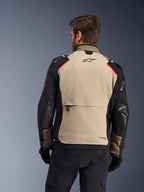 Casaco Alpinestars Andes Pro Drystar® XF, Vista Traseira, Walnut e Aluminum, com um grande painel traseiro bege com logótipo Alpinestars preto e detalhes vermelhos nos ombros, bolso de carga traseiro grande, usado com calças e luvas pretas, equipamento de motociclismo adventure touring