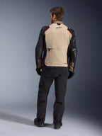 Casaco Alpinestars Andes Pro Drystar® XF, Walnut Aluminum, vista traseira, casaco de aventura para motociclista com mangas pretas e detalhes vermelhos nos ombros, usado com calças de condução e luvas pretas.