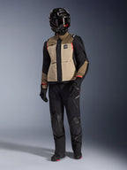 Casaco Alpinestars Andes Pro Drystar® XF em Walnut Aluminum, casaco de motociclismo de aventura usado com calças pretas a condizer, um capacete de aventura preto com óculos e botas pretas, com painéis beges e pretos e detalhes em vermelho.