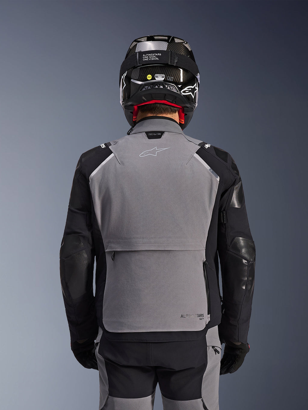 Alpinestars Andes Pro Drystar® XF Jacket, Dark Gray and Black, back view showing large rear storage pocket and Tech-Air branding, worn by a rider with a black helmet and matching riding pants, professional adventure touring gear