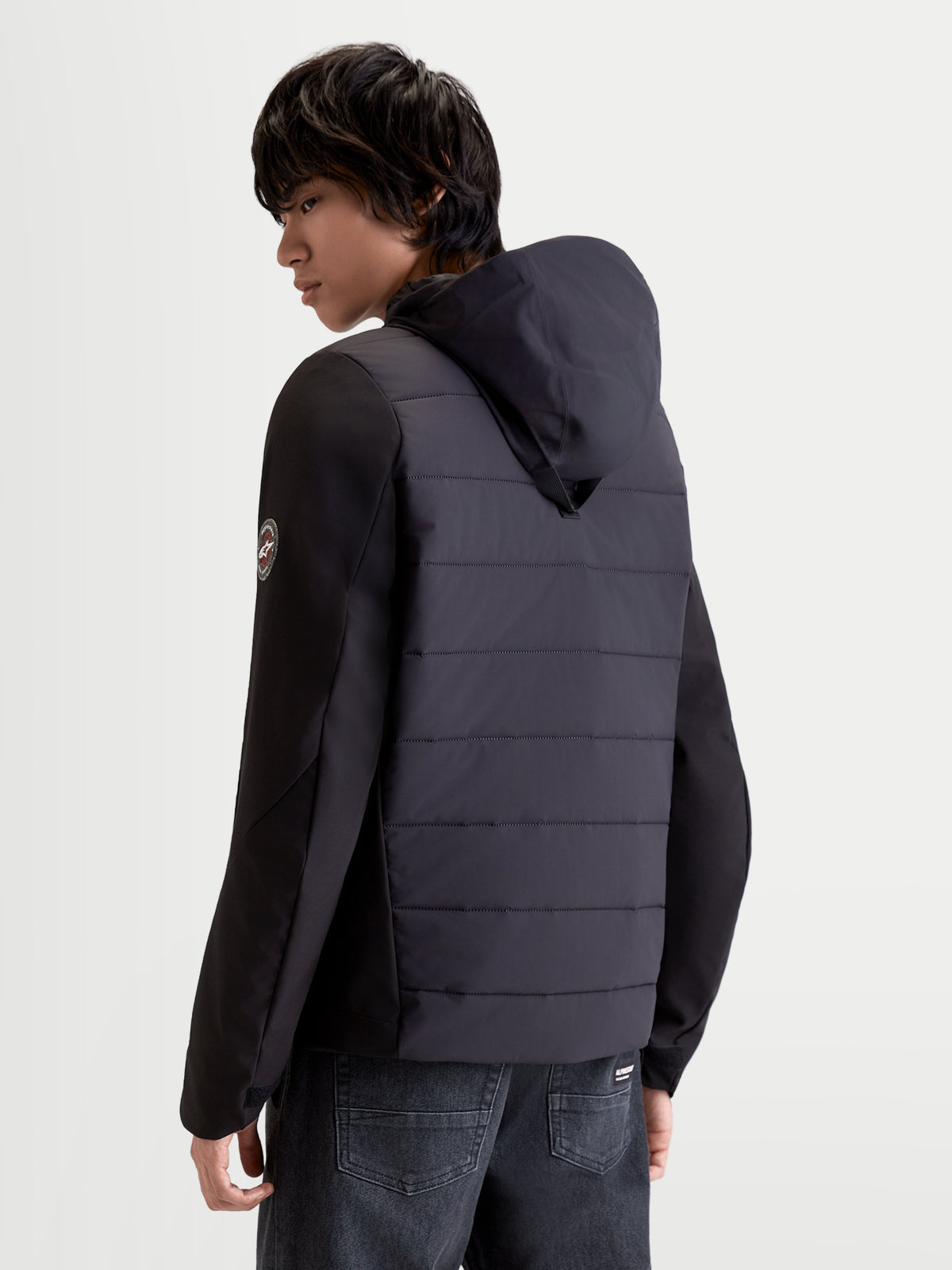 Alpinestars Therma Tech WP casaco de moto urbano para homem, preto, vista traseira de três quartos a mostrar construção acolchoada e capuz integrado num modelo
