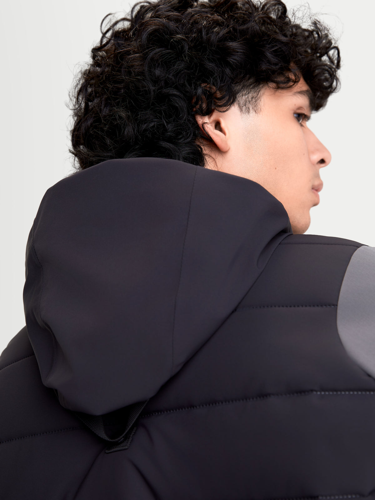Alpinestars Therma-Tech Waterproof Jacket, blusão de moto urbano para homem em preto e cinzento escuro, vista traseira em primeiro plano a mostrar o sistema de capuz integrado e a construção acolchoada soldada a ultrassons num modelo