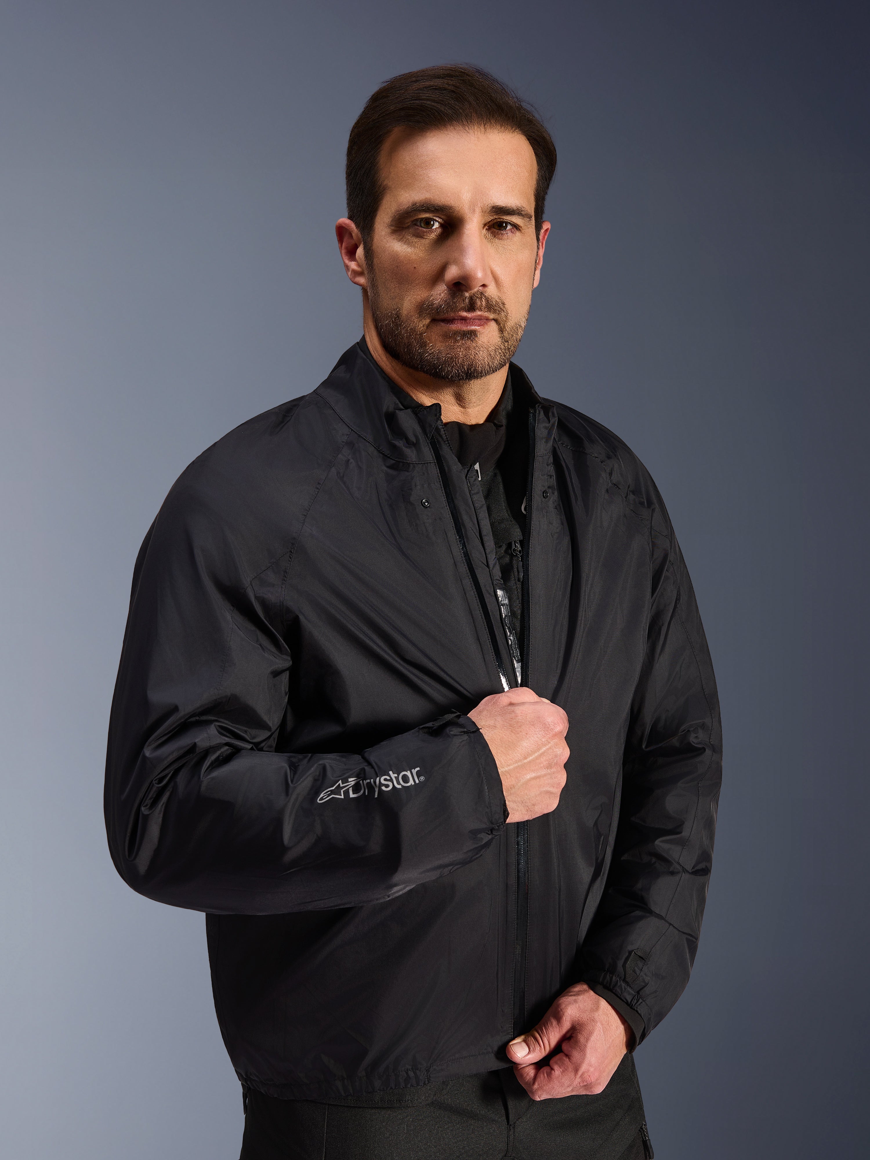 Alpinestars Cusco Drystar® Jacket, Black waterproof membrane layer worn by a male model, featuring Drystar logo on the sleeve, lightweight adventure touring motorcycle gear