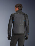 Casaco Alpinestars Cusco Drystar®, casaco de motociclismo, preto e cinzento escuro, vista traseira num modelo mostrando um grande painel traseiro cinzento, logótipo Alpinestars branco e detalhes azuis nas mangas.