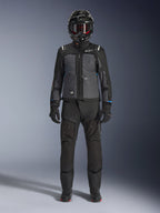 Casaco Alpinestars Cusco Drystar®, casaco de turismo de aventura preto e cinzento escuro, usado com calças pretas a condizer, luvas e um capacete integral, vista frontal de corpo inteiro, vestuário de proteção para motociclismo