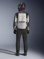 Motociclista visto de costas a usar o Casaco Alpinestars Cusco Drystar® em Ice Gray, Mid Gray e Deep Gray, com um grande painel de ventilação traseiro e logótipo Alpinestars, combinado com calças de condução pretas e capacete preto, vestuário de motociclismo adventure touring