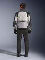 Vista traseira de um motociclista a usar o Casaco Alpinestars Cusco Drystar® em Ice Gray, Mid Gray e Deep Gray, combinado com calças e luvas de motociclismo pretas, destacando o amplo painel de ventilação traseiro e o logótipo Alpinestars.