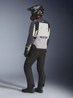 Casaco Alpinestars Cusco Drystar® em Ice Gray, Mid Gray e Deep Gray, vista traseira num motociclista. Apresenta pormenores em amarelo fluorescente, um grande painel de ventilação traseiro com a marca e construção têxtil durável. Usado com calças de motociclismo pretas e um capacete de aventura para um visual touring completo.