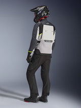 Alpinestars Cusco Drystar® Jacket in Ice Gray, Mid Gray, and Deep Gray, back view on a rider. Features fluorescent yellow accents, large back ventilation panel with branding, and durable textile construction. Worn with black motorcycle pants and an adventure helmet for a complete touring look.
