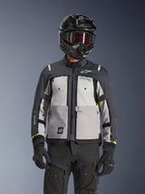 Alpinestars Cusco Drystar® Jacket, Adventure Touring Jacket, Ice Gray Mid Gray and Deep Gray, featuring multi-tonal gray panels, zippered chest vents, and Alpinestars branding, worn by a rider with a black helmet and goggles.