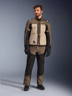 Casaco Alpinestars Cusco Drystar® em Walnut Aluminum Black, usado por um motociclista com calças de adventure touring a condizer, luvas e botas pretas, com painéis no peito em bege, mangas pretas com detalhes subtis em cor de laranja e fechos de ventilação funcionais para condução de motociclo em estrada.