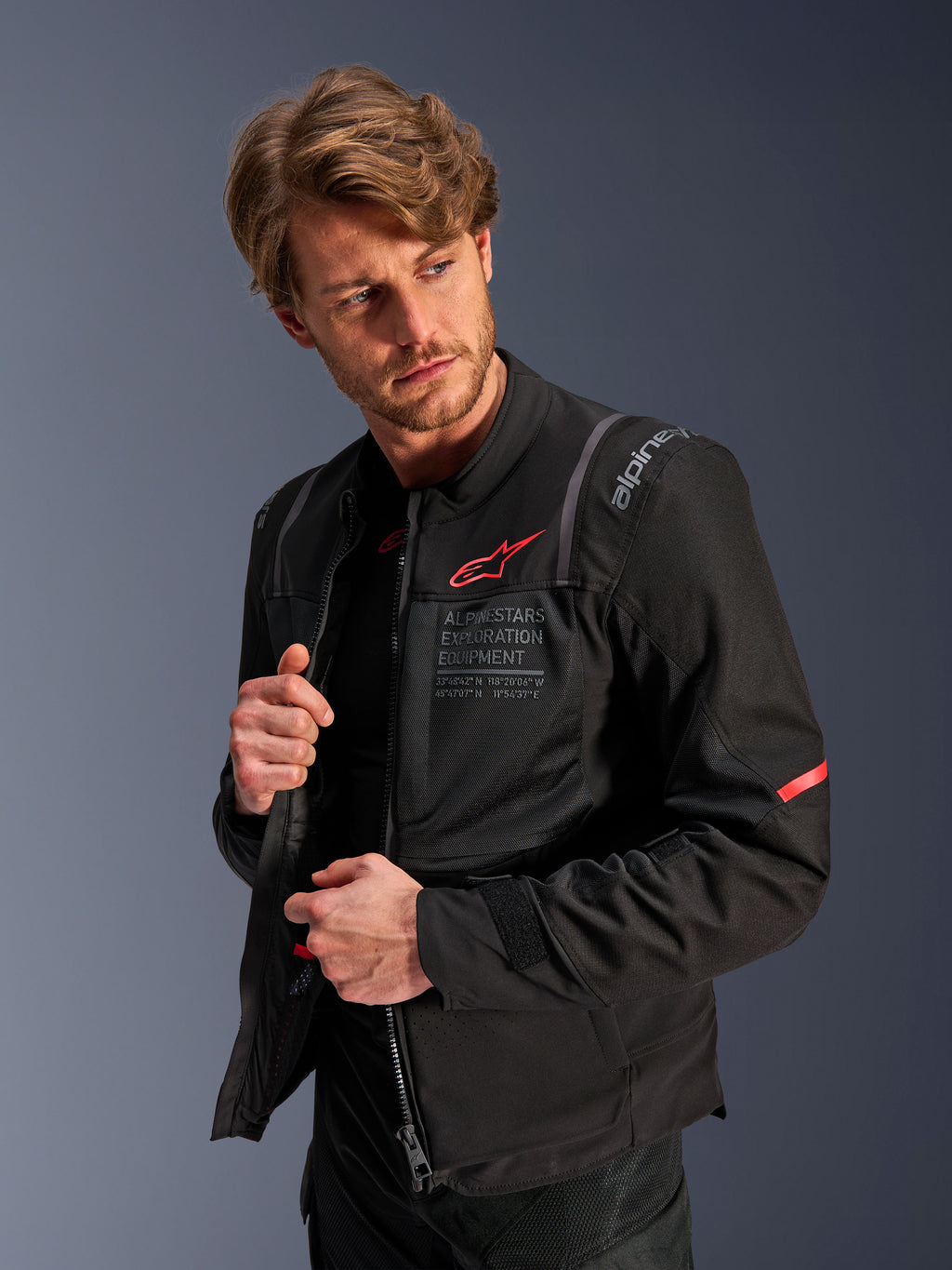 Alpinestars ST-2 Air Jacket, Black, summer motorcycle touring jacket with large mesh panels, featuring a red Astars logo and 'Alpinestars Exploration Equipment' text on the chest, modern technical design for airflow and protection worn by a model