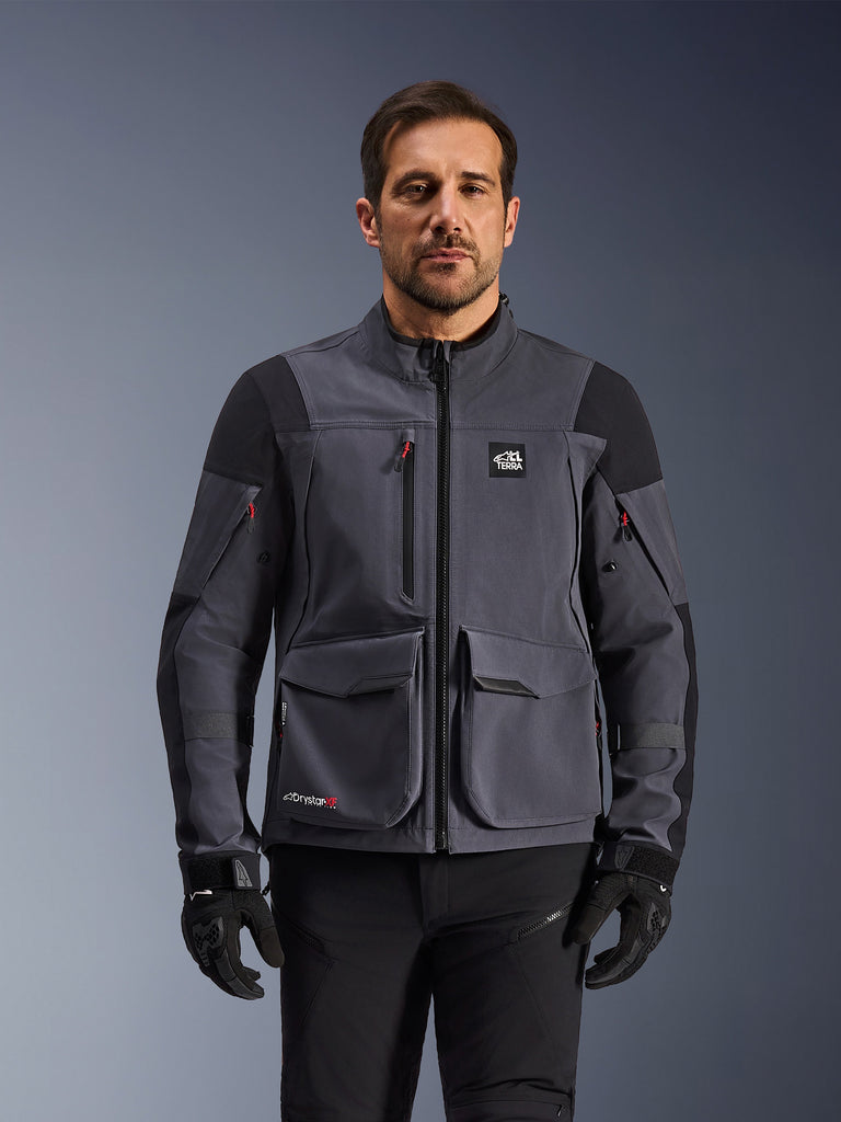 Alpinestars Maxdura Drystar®XF Laminated Armored Shell, Deep Gray and Black adventure motorcycle jacket, front view on model, featuring large cargo pockets, 'All Terra' chest logo, and ventilation zippers, paired with black riding gloves and pants.