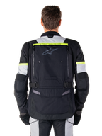 Alpinestars Bogota' Pro Drystar® Jacket, casaco de motociclismo adventure touring, preto, cinzento e amarelo néon, vista traseira mostrando a marca 'TECH TOURING' numa faixa amarela fluorescente, grande painel de ventilação traseiro e tiras de ajuste na cintura, equipamento técnico para todas as estações