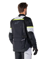 Casaco Alpinestars Bogotá Pro Drystar®, casaco de adventure touring, Preto, Ice Gray e Amarelo Fluo, vista traseira com grande painel de bolso traseiro e marca 'TECH TOURING', logótipo Alpinestars e detalhes fluorescentes, equipamento de condução em têxtil técnico
