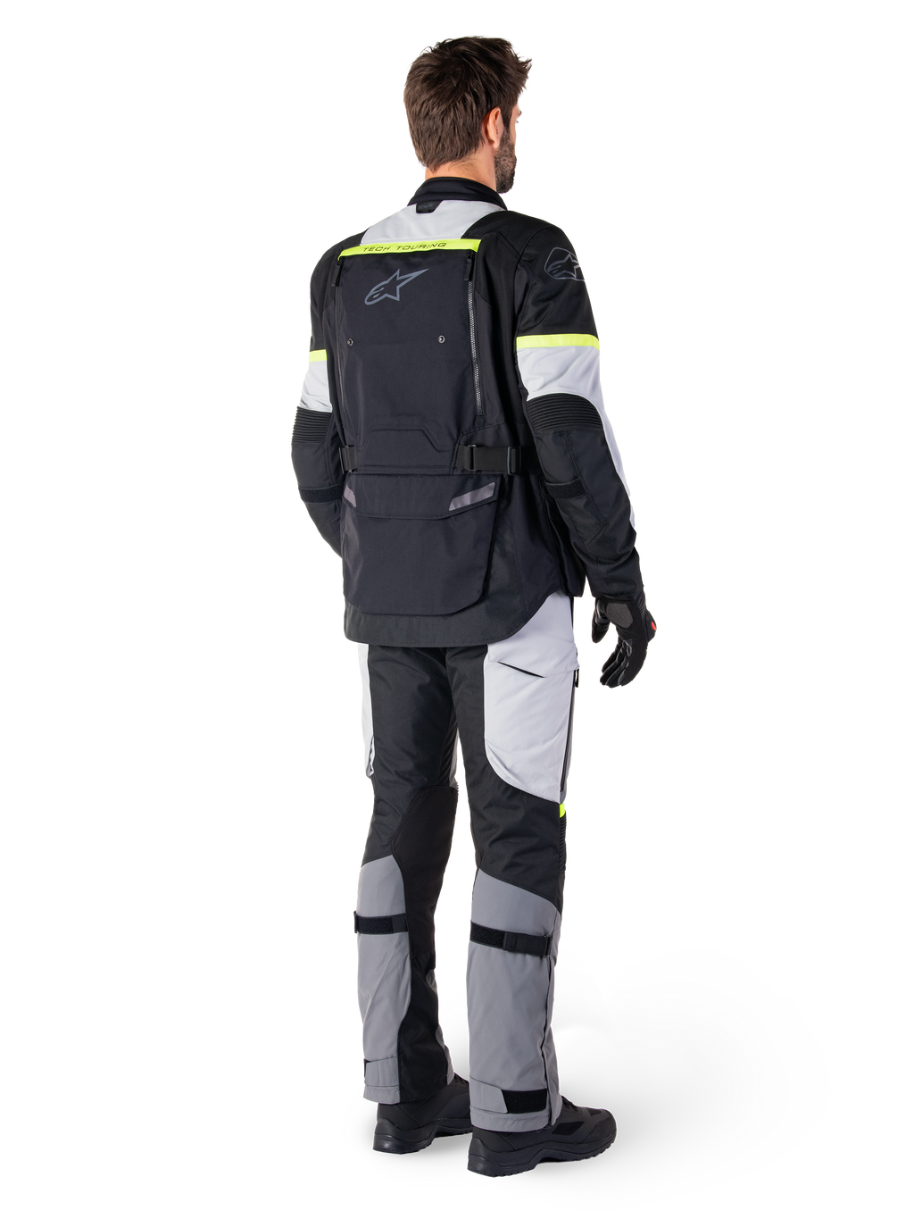 Vista traseira de um motociclista a vestir o Casaco Alpinestars Bogotá Pro Drystar® em Preto Ice Gray Amarelo Fluo, combinado com calças de adventure touring a condizer, com um bolso traseiro grande e detalhes em amarelo fluorescente, equipamento de motociclismo têxtil para todas as estações.