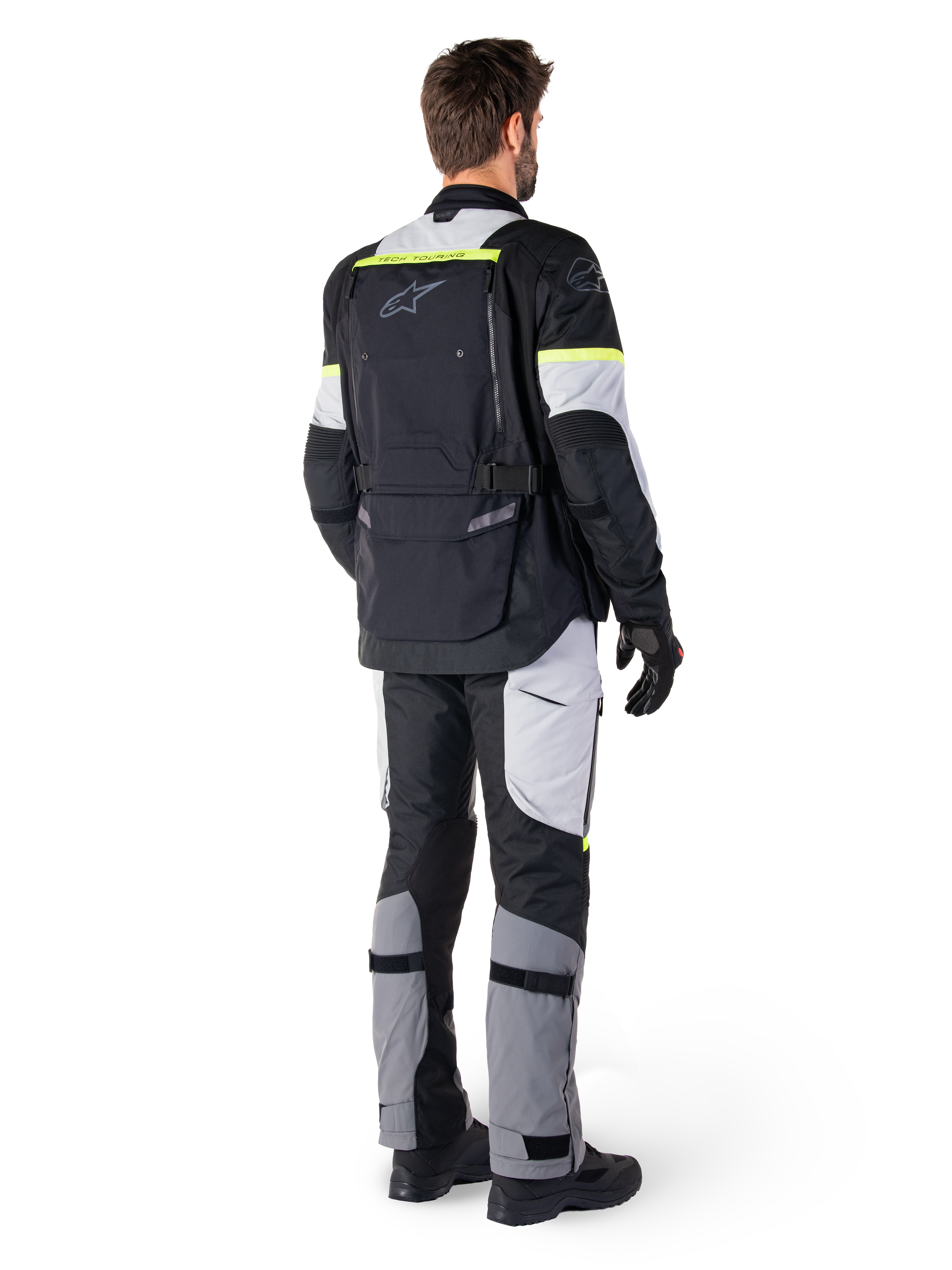 Vista traseira de um motociclista a vestir o Casaco Alpinestars Bogotá Pro Drystar® em Preto Ice Gray Amarelo Fluo, combinado com calças de adventure touring a condizer, com um bolso traseiro grande e detalhes em amarelo fluorescente, equipamento de motociclismo têxtil para todas as estações.