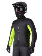Forro impermeável do casaco Alpinestars Bogotá Pro Drystar®, preto com detalhes em amarelo néon nas mangas, usado por um condutor com capacete preto e óculos de proteção, vestuário técnico de motociclismo