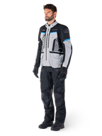 Male rider wearing Alpinestars Bogotá Pro Drystar® Jacket in Ice Gray, Black, and Cyan, paired with black technical riding pants and gloves, adventure touring gear for all-weather performance.