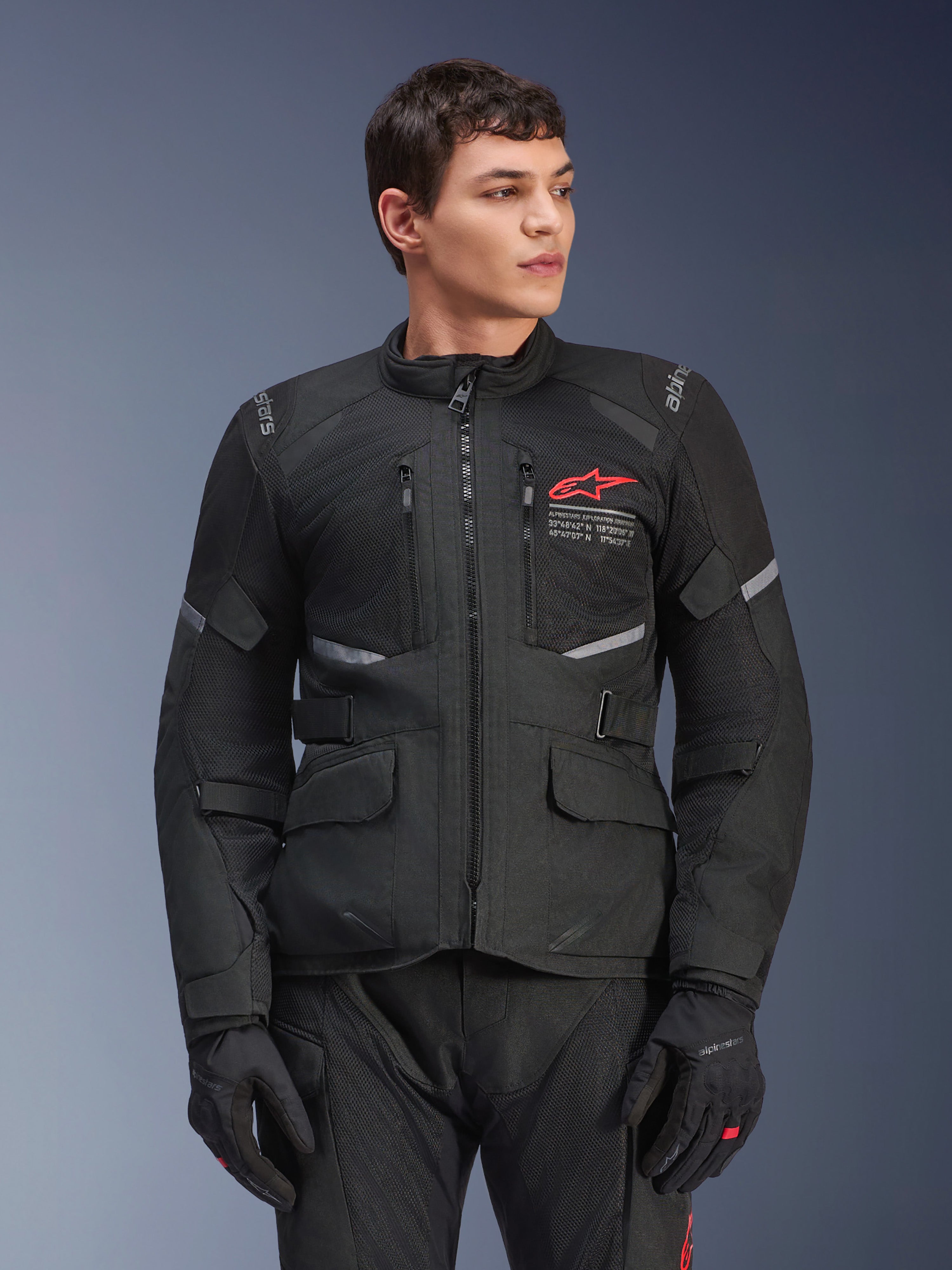 Casaco Alpinestars Andes Air Drystar®, casaco de motociclismo touring preto, logótipo de estrela vermelha no peito, com painéis de ventilação em malha e detalhes refletores, usado por modelo masculino com luvas de condução pretas, equipamento de aventura para duas estações
