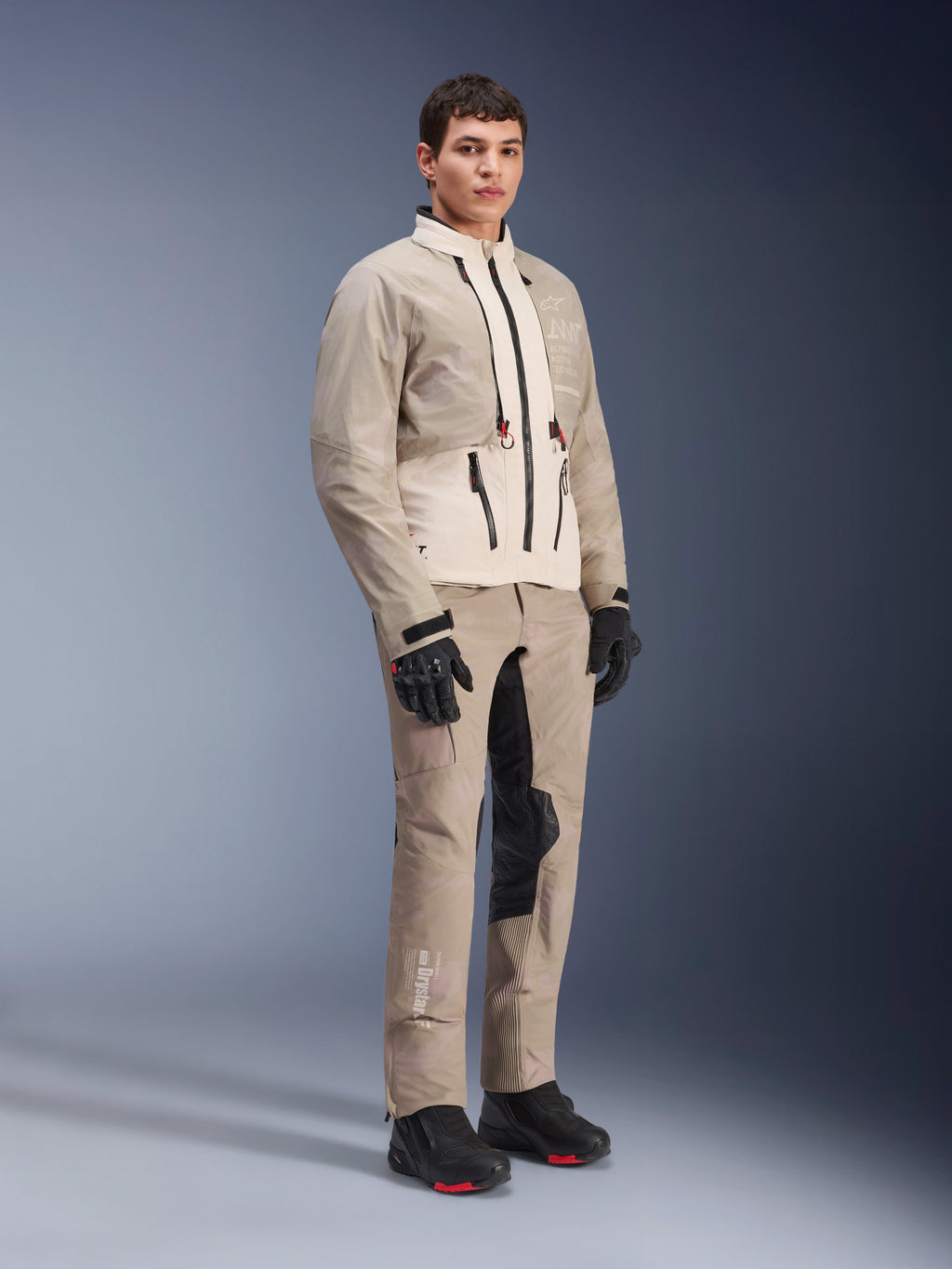 Calças Alpinestars AMT-10LAB Drystar® XF e casaco a condizer, equipamento de aventura Aluminum Camo, conjunto completo com luvas e botas pretas, com branding técnico e painéis de proteção modulares, fotografia de estilo de vida em estúdio