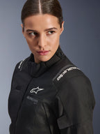 Casaco Alpinestars Stella Andes V4 Drystar® para Mulher, casaco de motociclismo preto, retrato de estúdio em grande plano que mostra a parte superior do tronco e o ombro, com logótipos Alpinestars brancos, material têxtil de alta qualidade e um corte feminino elegante