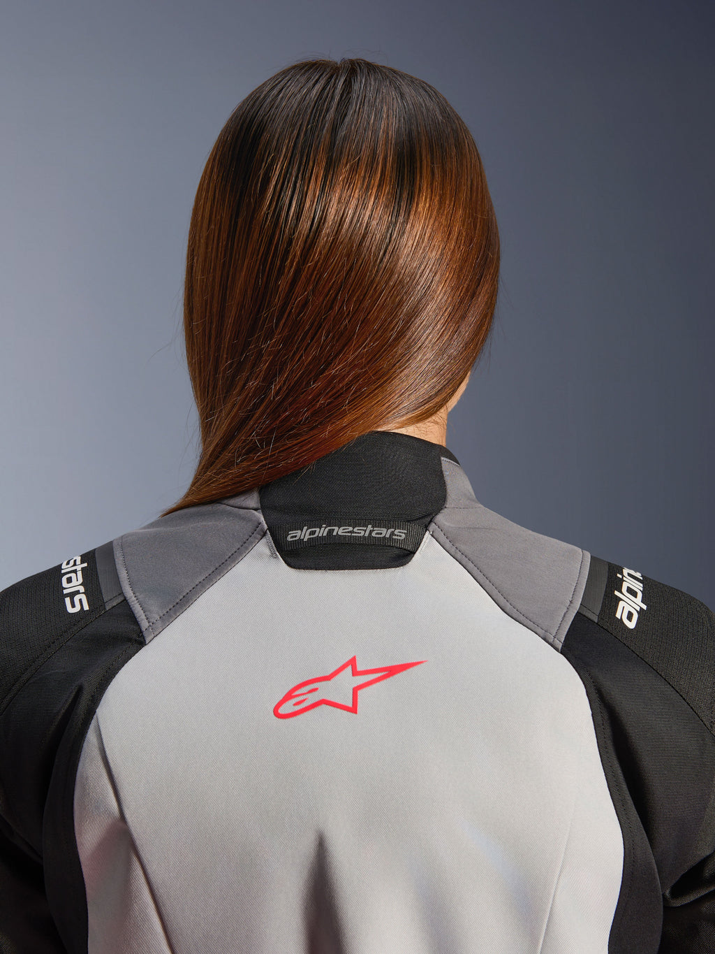 Alpinestars Stella Andes V4 Drystar, casaco de moto de aventura para mulher, impermeável, cinzento gelo e preto, pormenor do logótipo coral fluo nas costas e colarinho.