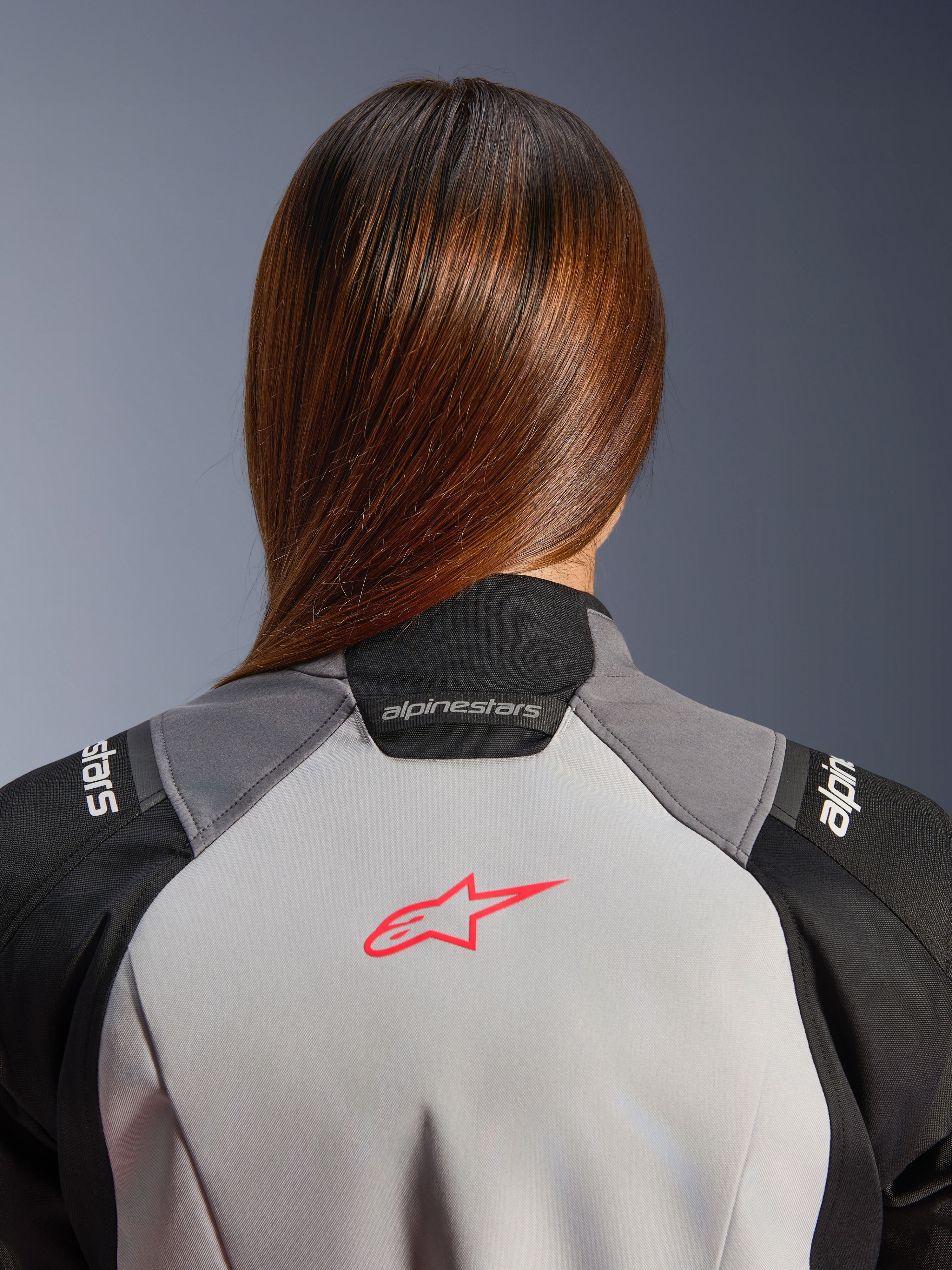 Alpinestars Stella Andes V4 Drystar, casaco de moto de aventura para mulher, impermeável, cinzento gelo e preto, pormenor do logótipo coral fluo nas costas e colarinho.