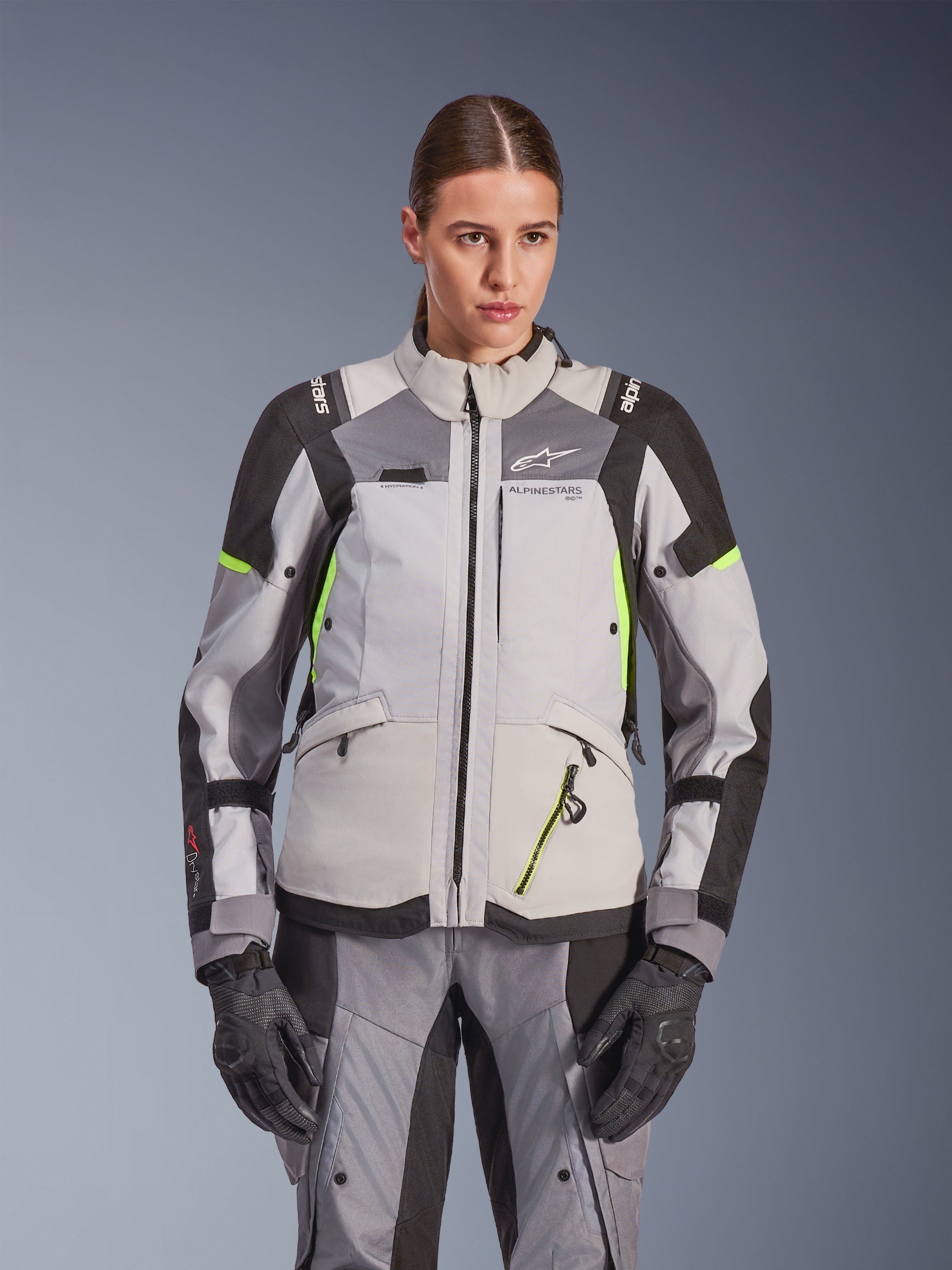 Alpinestars Stella Andes V4 Drystar® Jacket para Mulher, cinzento gelo e cinzento escuro com pormenores em amarelo néon, casaco de motociclismo de aventura, usado com calças e luvas a condizer, com construção têxtil protetora e logótipo Alpinestars.