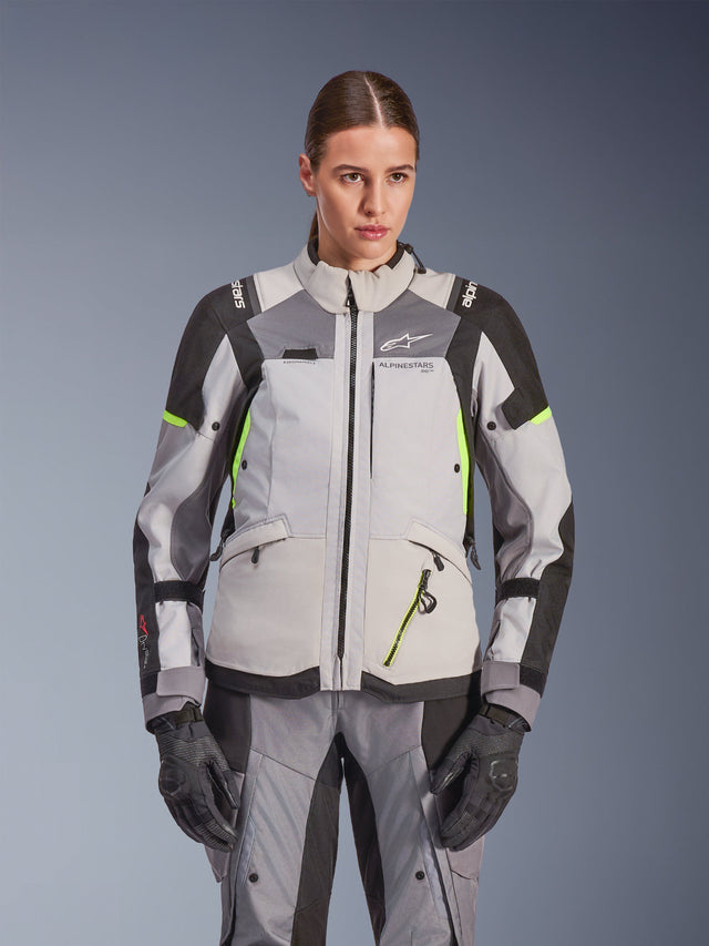 Alpinestars Stella Andes V4 Drystar® Jacket para Mulher, cinzento gelo e cinzento escuro com pormenores em amarelo néon, casaco de motociclismo de aventura, usado com calças e luvas a condizer, com construção têxtil protetora e logótipo Alpinestars.