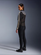 Modelo feminina vista de lado e de costas a usar o Casaco Alpinestars Stella T-Dyno WR em Preto Cinzento Escuro Ecru, com um design de inspiração vintage, riscas ecru nas mangas e um painel traseiro cinzento, combinado com calças pretas e calçado de motociclismo preto.
