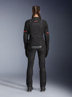 Casaco Alpinestars Stella ST-2 Air, casaco de motociclismo para mulher, preto, vista traseira com logótipo vermelho na parte superior das costas e marca cinzenta na parte inferior das costas, usado com calças e botas de motociclismo pretas a condizer, design touring moderno com painéis de malha e detalhes refletores